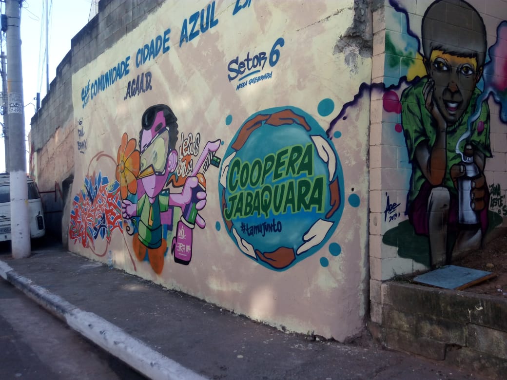 Muro grafitado com o logotipo do Coopera e os dizeres "setor 6" e "Cidade azul" e um desenho de um personagem. 
